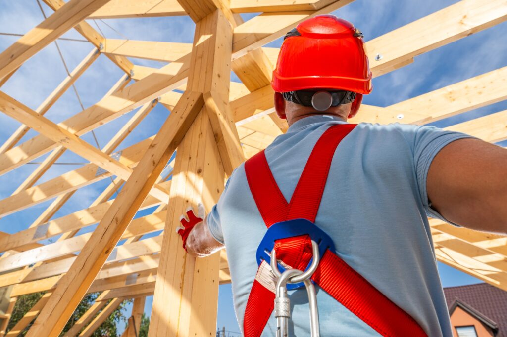 Construction Worker Guiding Framework Assembly at a Building Site Under a Clear Blue Sky