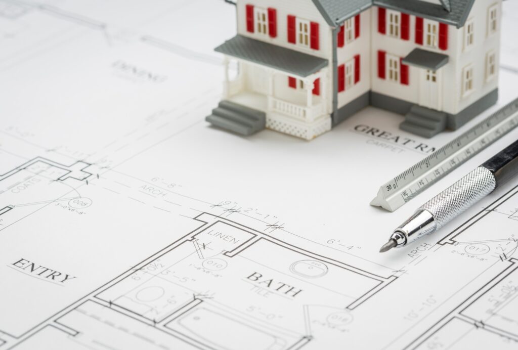 Model Home, Engineer Pencil and Ruler Resting On Custom House Plans.