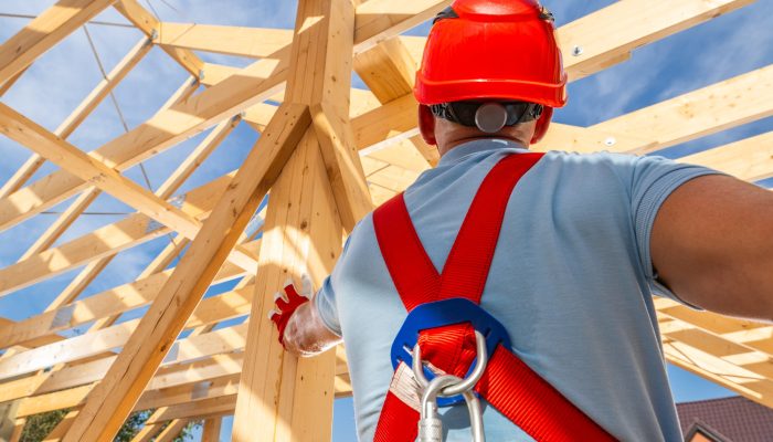 Construction Worker Guiding Framework Assembly at a Building Site Under a Clear Blue Sky