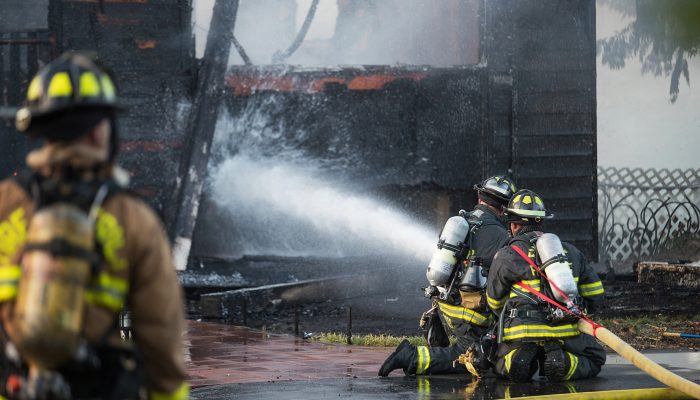 Firefighter sprays water on burning house fire